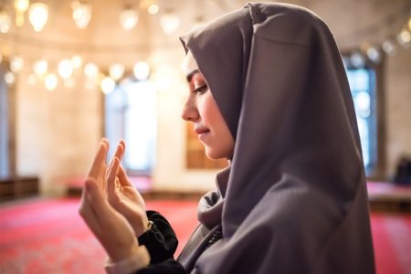 Muslim woman in headscarf and an hijab prays